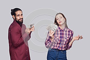 Portrait of rich serious woman with fan of money and near sad poor man, standing and looking at camera