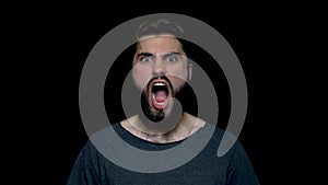 Portrait of roar handsome man with beard standing and screaming with big open mouth, isolated on black background. Young