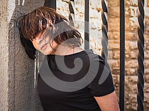 Portrait of a romantic beautiful 65-year-old brunette against the background of an old wall and forged lattice. Close-up image,