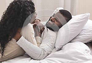Portrait of romantic black couple spending time in bed together