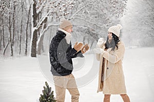 Portrait of romantic couple playing in snowballs in forest at winter day