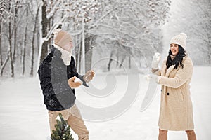 Portrait of romantic couple playing in snowballs in forest at winter day