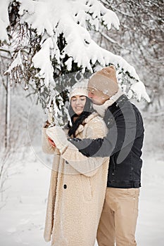 Portrait of romantic couple spending time together in forest at winter day