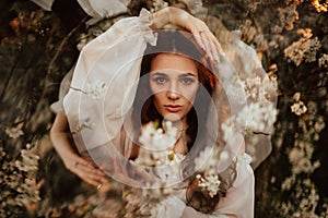 Portrait of a romantic girl in a blooming garden with elements of phantasmagoria. The concept of fantasy, fairy tales.