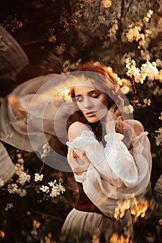 Portrait of a romantic girl, like a forest nymph, in a blooming garden with elements of phantasmagoria. The concept of