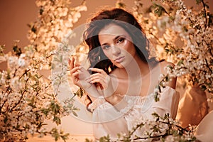 Portrait of a romantic girl sitting in a blooming garden. The concept of fantasy and fairy tales