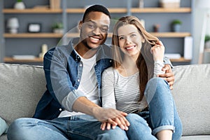 Portrait Of Romantic Multicultural Couple Relaxing On Couch At Home And Hugging