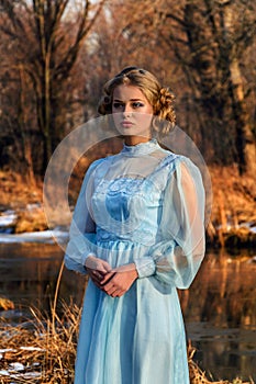 Portrait of romantic woman in a dress on the bank of the river
