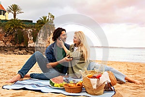 Portrait Of Romantic Young Couple Having Picnic On Beach Near Sea