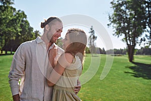 Portrait of romantic young couple looking at each other, posing together outdoors while standing in the park