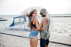 Portrait of romantic young couple standing at the wooden pier