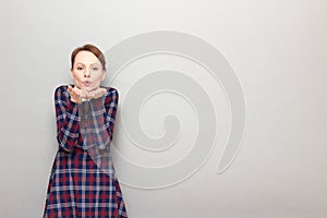 Portrait of romantic young woman blowing air kiss to you