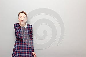 Portrait of romantic young woman blowing air kiss to you