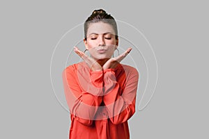 Portrait of romantic young woman with bun hairstyle, big earrings and in red blouse. indoor studio shot isolated on gray