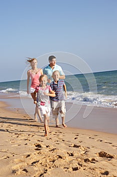 Portrait Of Running Family On Beach