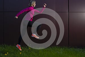 Portrait of Running Mature Sportswoman During Outdoor Active Jogging Training Against Abstract Wall Background