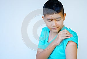 Portrait of rural Asian boy standing against white background looking at plaster on his arm from the coronavirus vaccinated in