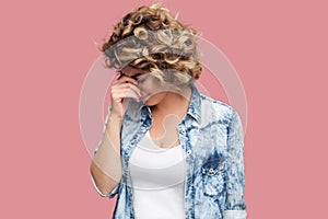 Portrait of sad alone depressed young woman with curly hairstyle in casual blue shirt standing and holding head down and crying