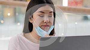 Portrait sad asian business woman girl student takes off medical face mask exhales with relief work project with laptop