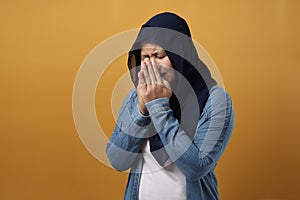 Portrait of sad Asian muslim woman crying against yellow background, sadness depression hopeless