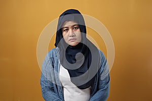 Portrait of sad Asian muslim woman crying against yellow background, sadness depression hopeless