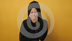 Portrait of sad Asian muslim woman crying against yellow background, sadness depression hopeless