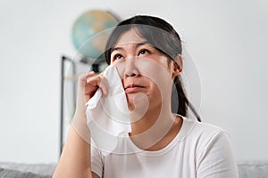 Portrait of a Sad Asian woman crying wipes her tears with a tissue paper towel