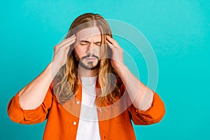 Portrait of sad blond hair man in bad mood wearing orange clothes touching temples feel stressed isolated on cyan color