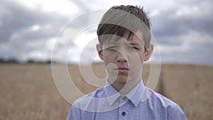 Portrait of a sad boy on a wheat field close up outdoors