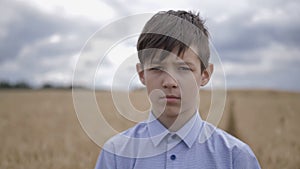 Portrait of a sad boy on a wheat field close up outdoors