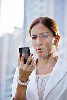 Portrait sad business woman typing sms phone street