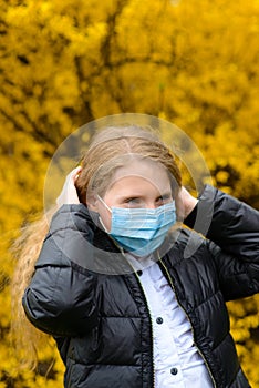 Portrait of sad caucasian child in face mask on closed playground outdoor. Coronavirus social distance quarantine