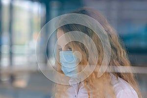 Portrait of sad caucasian child in face mask on closed playground outdoor. Coronavirus social distance quarantine