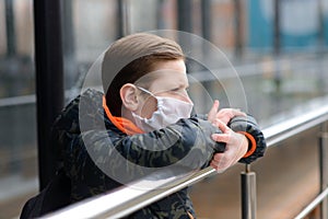 Portrait of sad caucasian child in face mask on closed playground outdoor. Coronavirus social distance quarantine