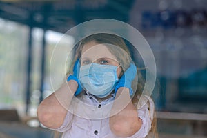 Portrait of sad caucasian child in face mask on closed playground outdoor. Coronavirus social distance quarantine