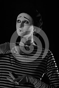 Portrait of sad crying mime on black background. Portrait of a male mime artist standing under umbrella expressing sadness and lon