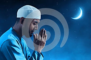 Portrait of sad crying young asian muslim man with beard pray at beautiful blue night sky