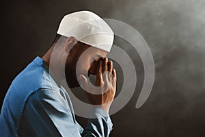 Portrait of sad crying young asian muslim man with beard praying on dark backgrounds