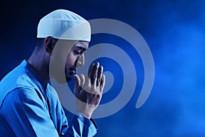 Portrait of sad crying young asian muslim man with beard praying on dark blue backgrounds