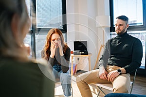 Portrait of sad crying young woman sharing problem sitting in circle during group therapy session.