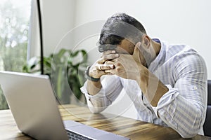 Portrait of a sad and depress mexican businessman working at modern home office with computer laptop