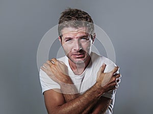 Portrait of sad and depressed man hugging and embracing himself desperate feeling frustrated and helpless in depression and sadnes