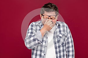 Portrait of sad depressed middle aged business man in casual checkered shirt and eyeglasses standing holding head down and crying