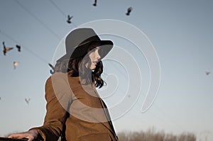 Portrait of sad elegant girl outdoor with pigeons in the autumn sky