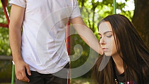 Portrait of a sad girl with dark hair. Sad man comes to the girl and hugs her head. Medium shot.