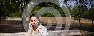 Portrait of sad girl talking on mobile phone and sulking. Young woman having an uneasy conversation on telephone