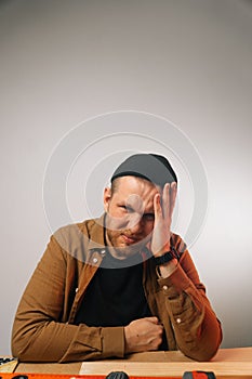 Portrait of a sad handsome caucasian male fitter in uniform. Woodworking workshop in a factory