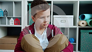 Portrait of sad kid sitting on floor at home sighing feeling bored and unhappy