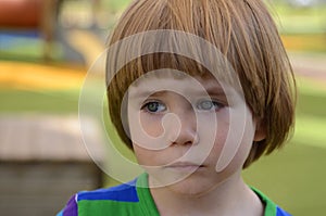 Portrait of a sad little boy in playground