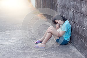 Portrait of a sad and lonely Asian girl against grunge wall back